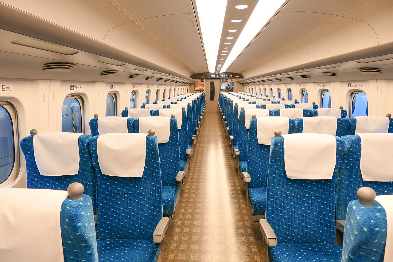 青い座席が3席と2席ずつ並ぶN700A新幹線の普通車内